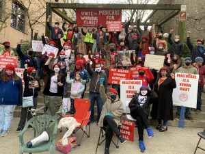 Crowd of volunteers with raised fists and Medicare for All signs