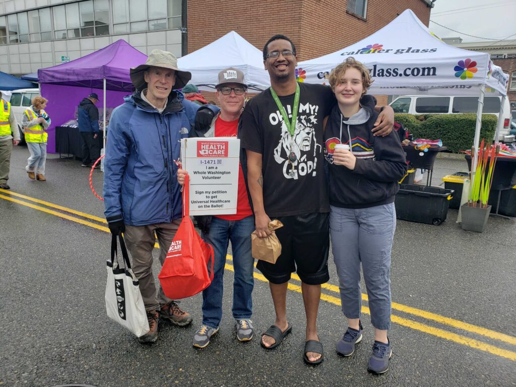 Four new friends at farmers market with a volunteer sign