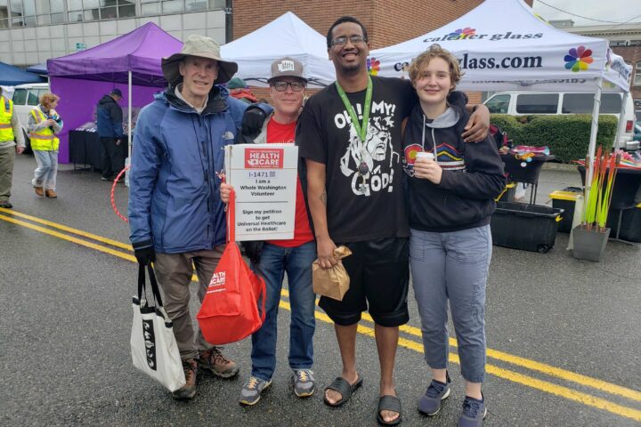Four new friends at farmers market with a volunteer sign